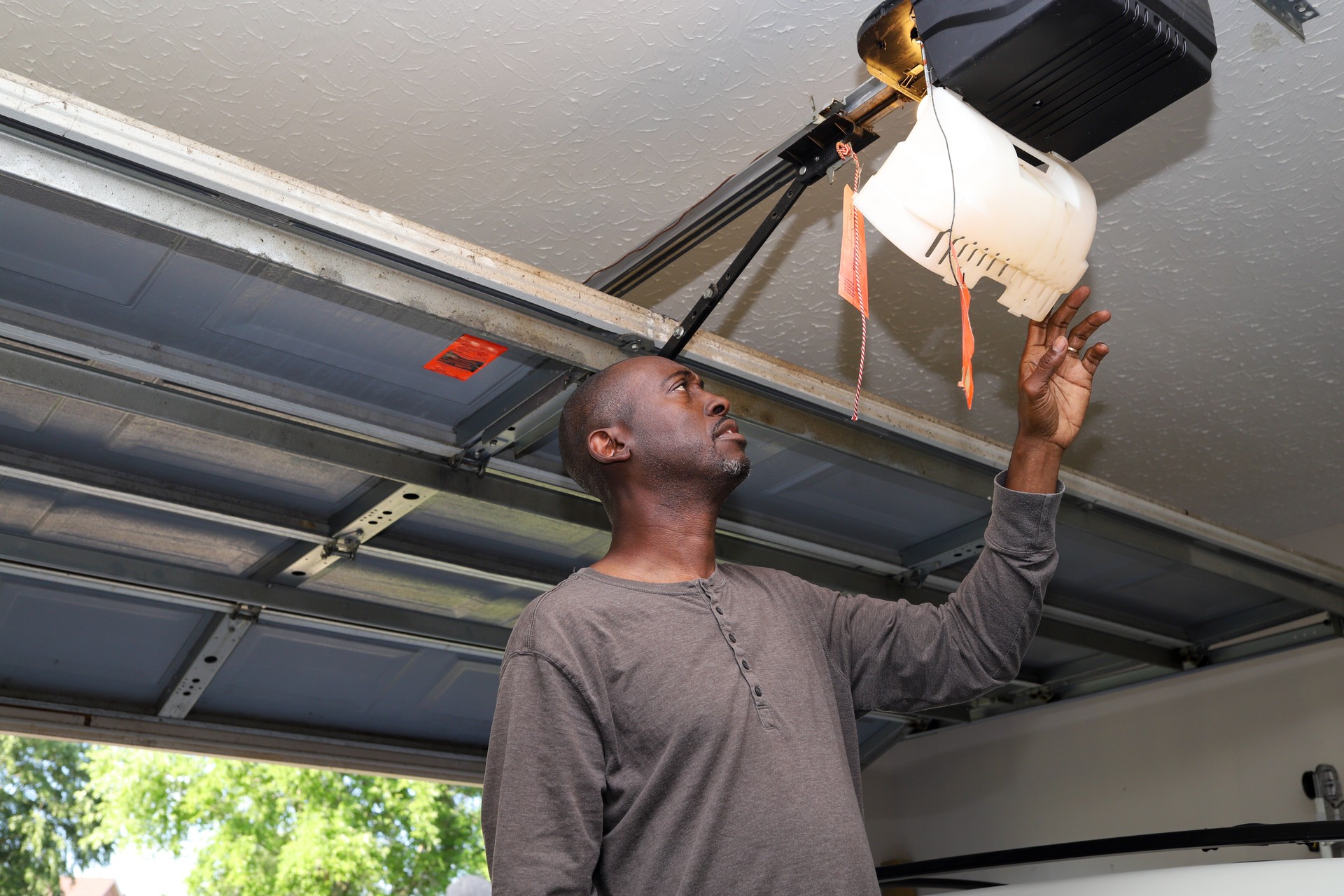 A portrait of a black African-American man changing a lightbulb in a overhead garage